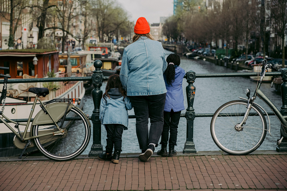 Frau mit Fahrrad auf Brücke beim Sightseeing an der Gracht in Amsterdam
