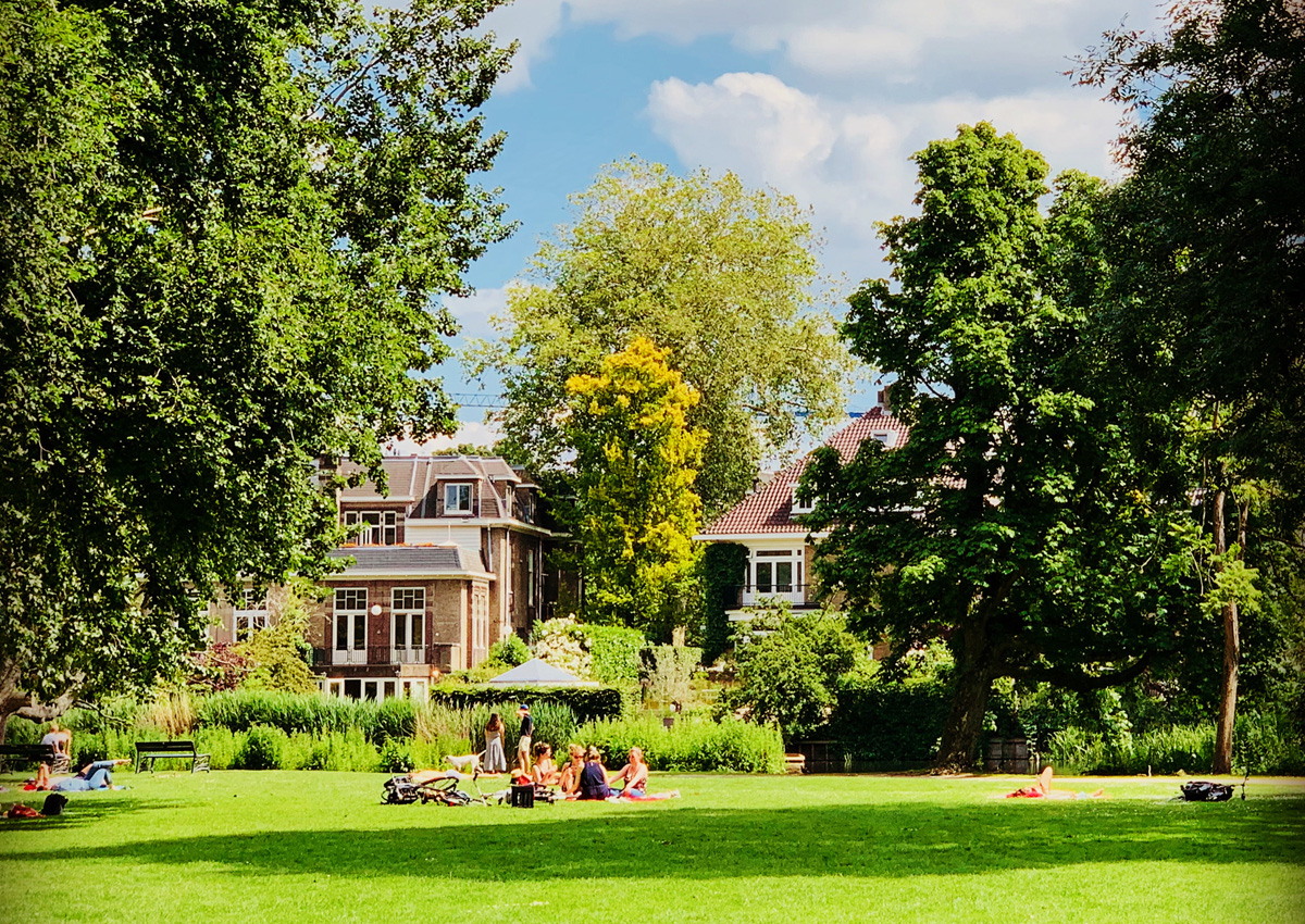 Menschen entspannen auf den Wiesen im Vondelpark Amsterdam an einem sonnigen Tag